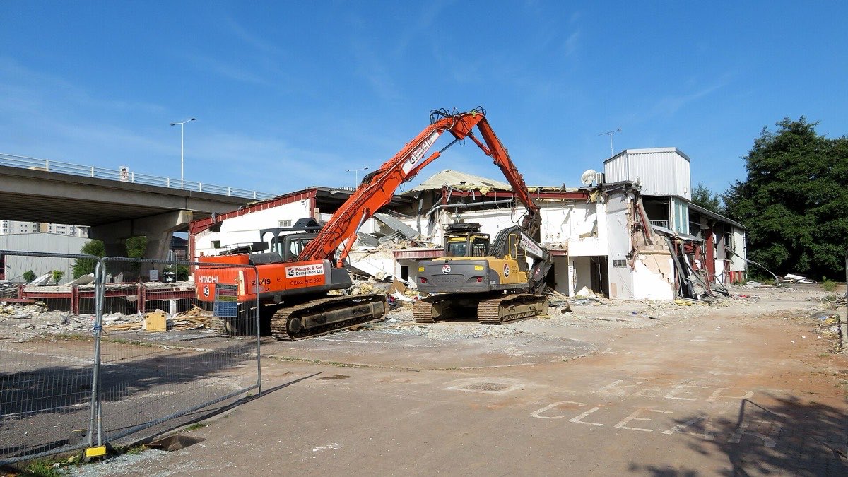 Excavators with demolition shears tearing down an industrial building